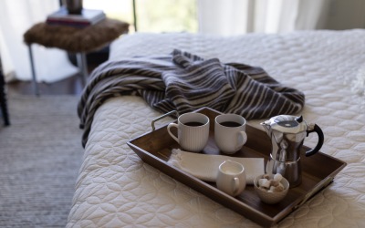 a tray on a bed with teacups and surrounded by natural lighting