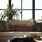 living room with a large couch, decorative pillows with foliage and ample natural lighting